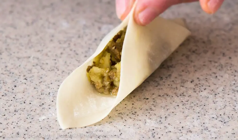 Seasoned beef and onions, tucked away in a tender wrapper, and topped with an herby yogurt sauce make this delicious recipe for Afghan mantu, or dumplings, a perfect crowd pleaser for your next party!